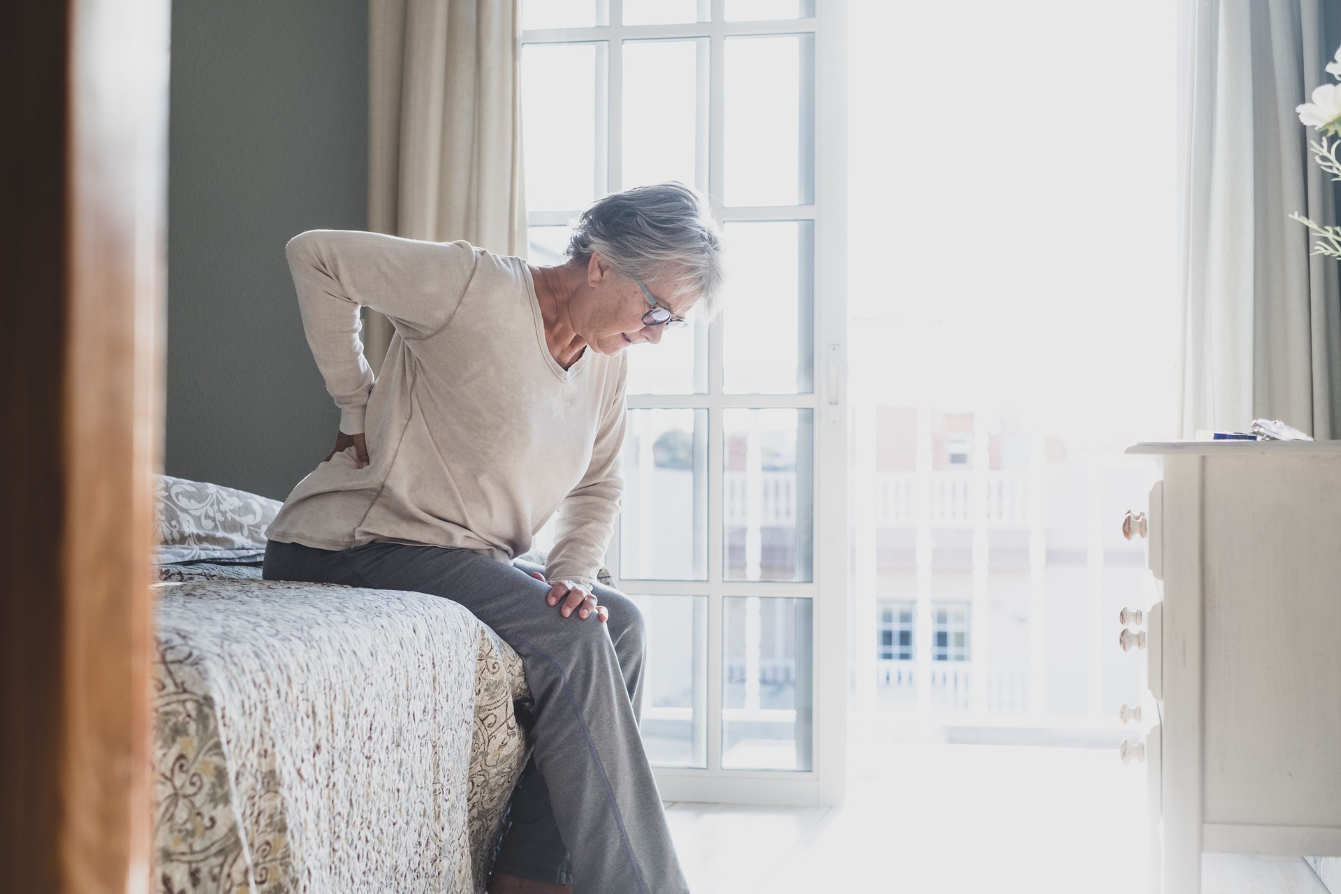Side View Of Senior Woman Resting On Bed At Home